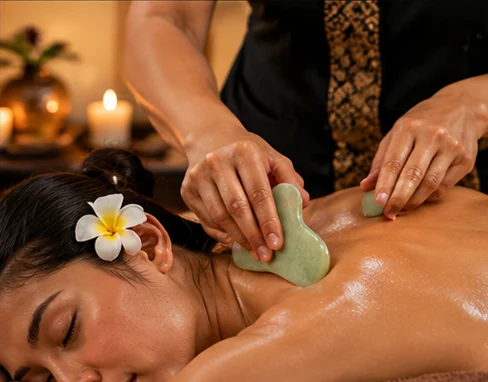 Massage therapist using a smooth gua sha tool on a client's upper back to target muscle tension at a Newport Beach massage studio.