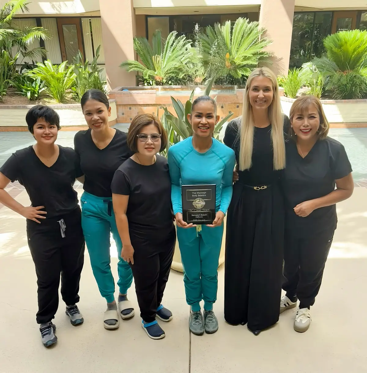 Six Thai Massage Body Balance therapists standing together outside the Newport Beach studio holding their Best of Business award