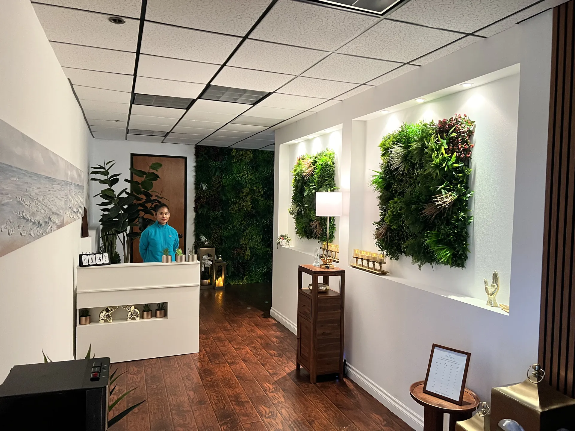 Full depth view of the lobby with a therapist at the desk, green walls and wall sconces