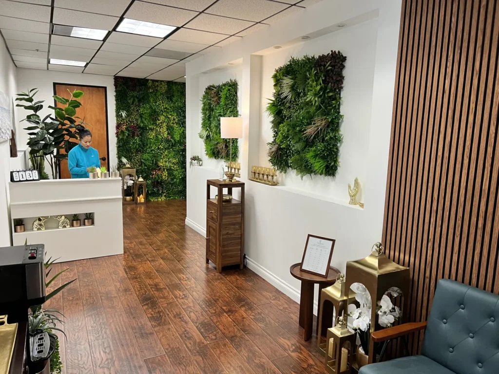 Reception desk at Thai Massage Body Balance flanked by living green walls and warm lighting
