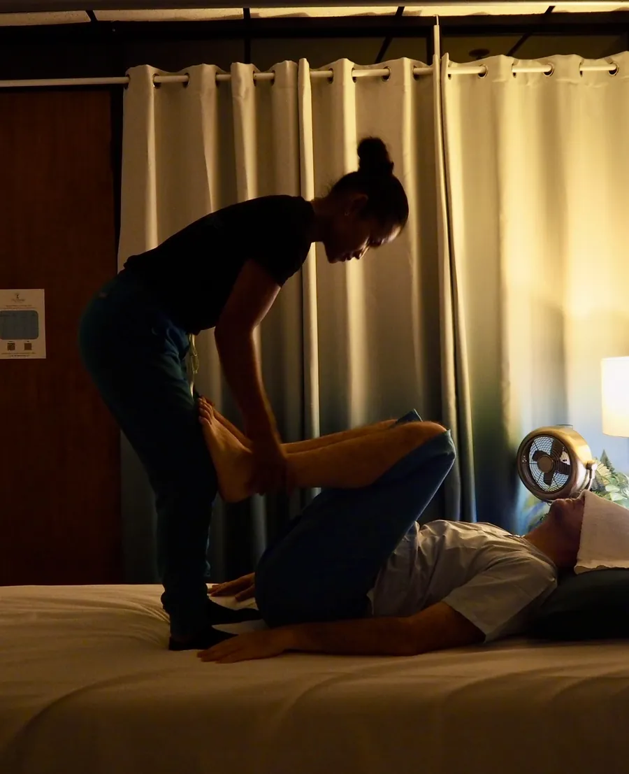 Therapist applying a traditional Thai back stretch to a client lying on the table